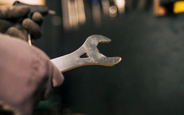 Main gantée de technicien avec clé à molette tenu dans la main droite et un autre outil dans la main gauche